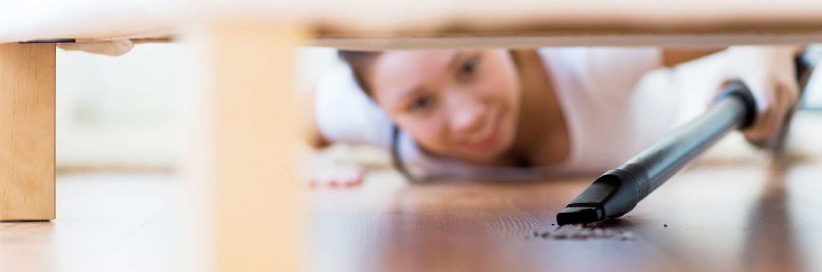 A cleaner vacuuming under a cupboard